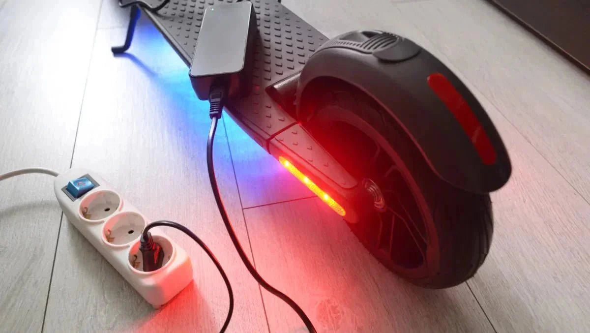 Patinete eléctrico cargando en casa con el cargador enchufado a una regleta – cómo aumentar la autonomía
