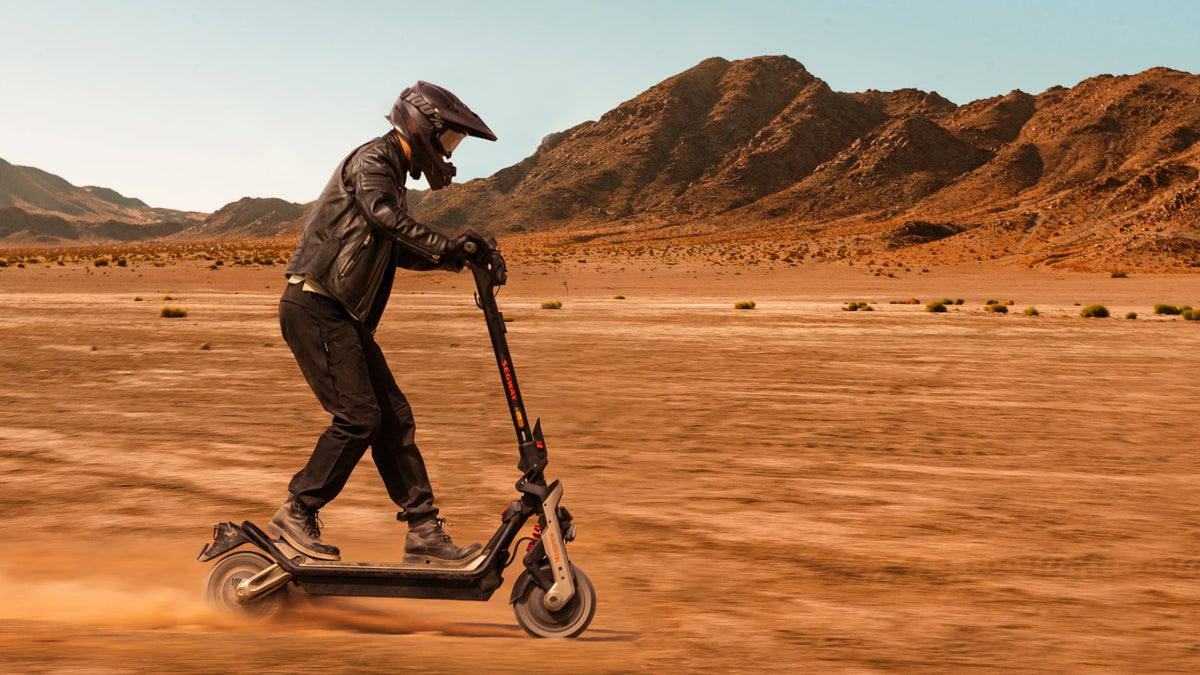 Conductor con casco en un patinete eléctrico Ninebot GT3 sobre una llanura de arena – patinete para personas pesadas