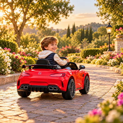 Niño conduciendo el coche eléctrico para niños Mercedes AMG GT en color rojo en un parque