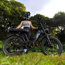Mujer montando la bicicleta eléctrica fat bike TST R7 en color negro sobre el césped