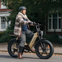 Persona montando la bicicleta eléctrica fat bike TST R7 en color beige por una calle