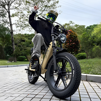 Hombre montando la bicicleta eléctrica fat bike TST R7 en color negro por un camino peatonal