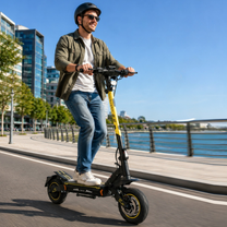 Hombre con casco conduce un patinete eléctrico Wheely - H7 por un muelle junto al agua