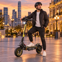Hombre con casco apoyando un pie en un patinete eléctrico negro y amarillo en una plaza al anochecer