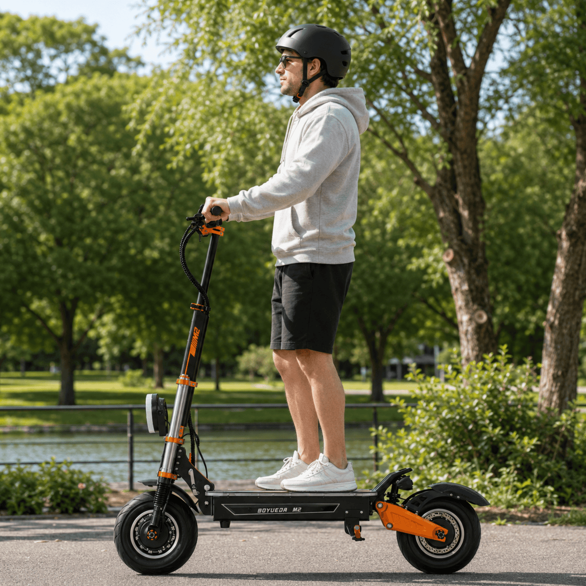 Hombre de pie junto al patinete eléctrico BOYUEDA M2 en un parque