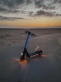 Patinete eléctrico DUALTRON POPULAR en vista frontal en ángulo junto al mar al atardecer