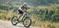Hombre montando la bicicleta eléctrica fat bike Duotts E26 por un camino peatonal