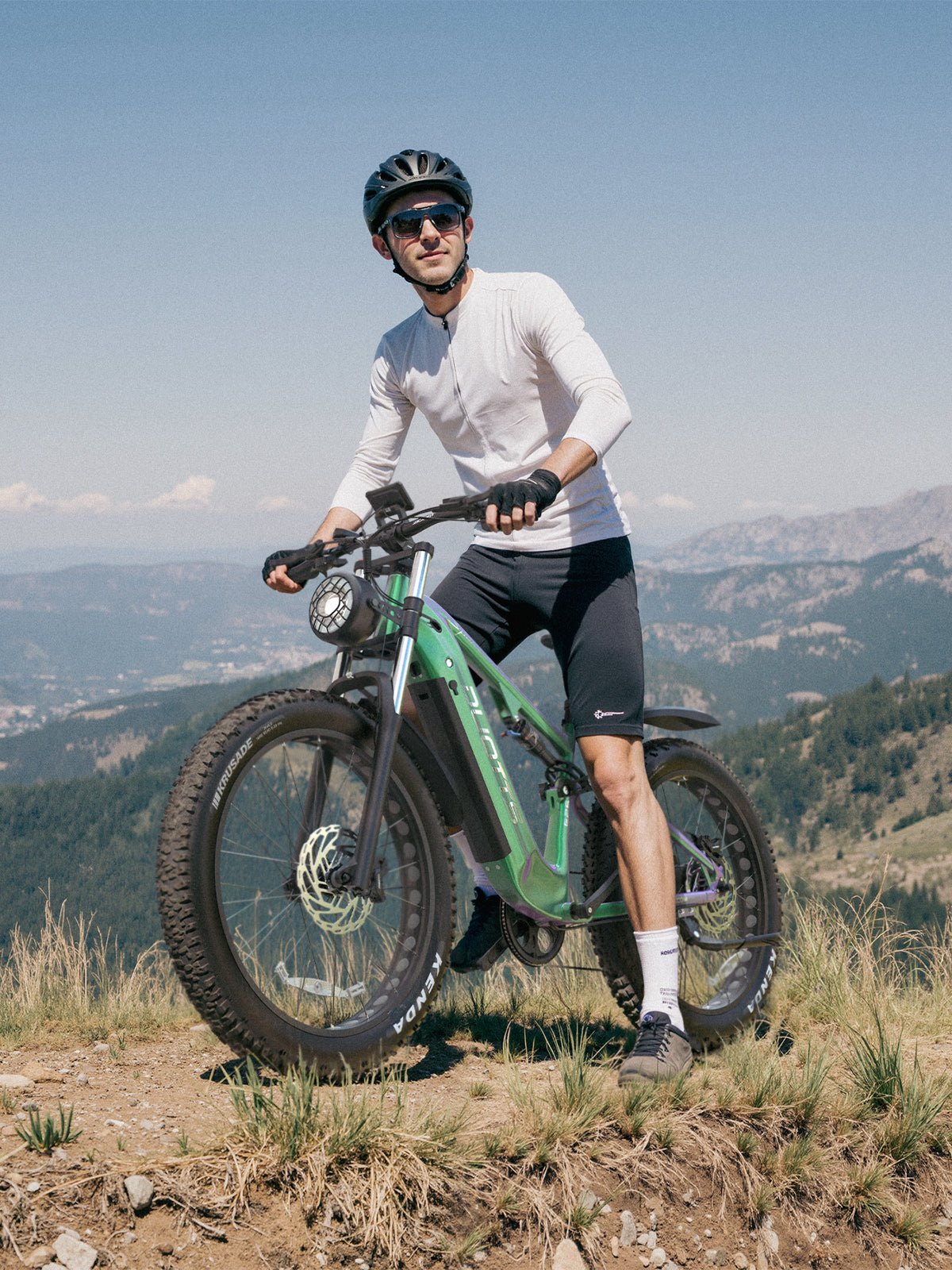 Hombre de pie junto a la bicicleta eléctrica fat bike Duotts E26 sobre el césped