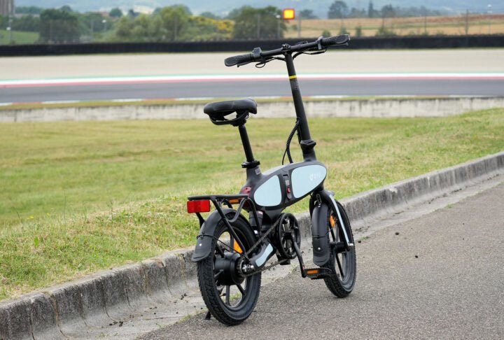 Bicicleta eléctrica plegable DYU C2, vista trasera en ángulo en un camino peatonal