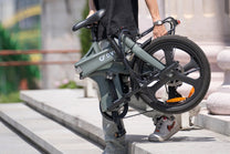 Persona llevando la bicicleta eléctrica plegable DYU T1 plegada