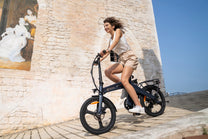 Mujer montando la bicicleta eléctrica plegable DYU T1 por la ciudad
