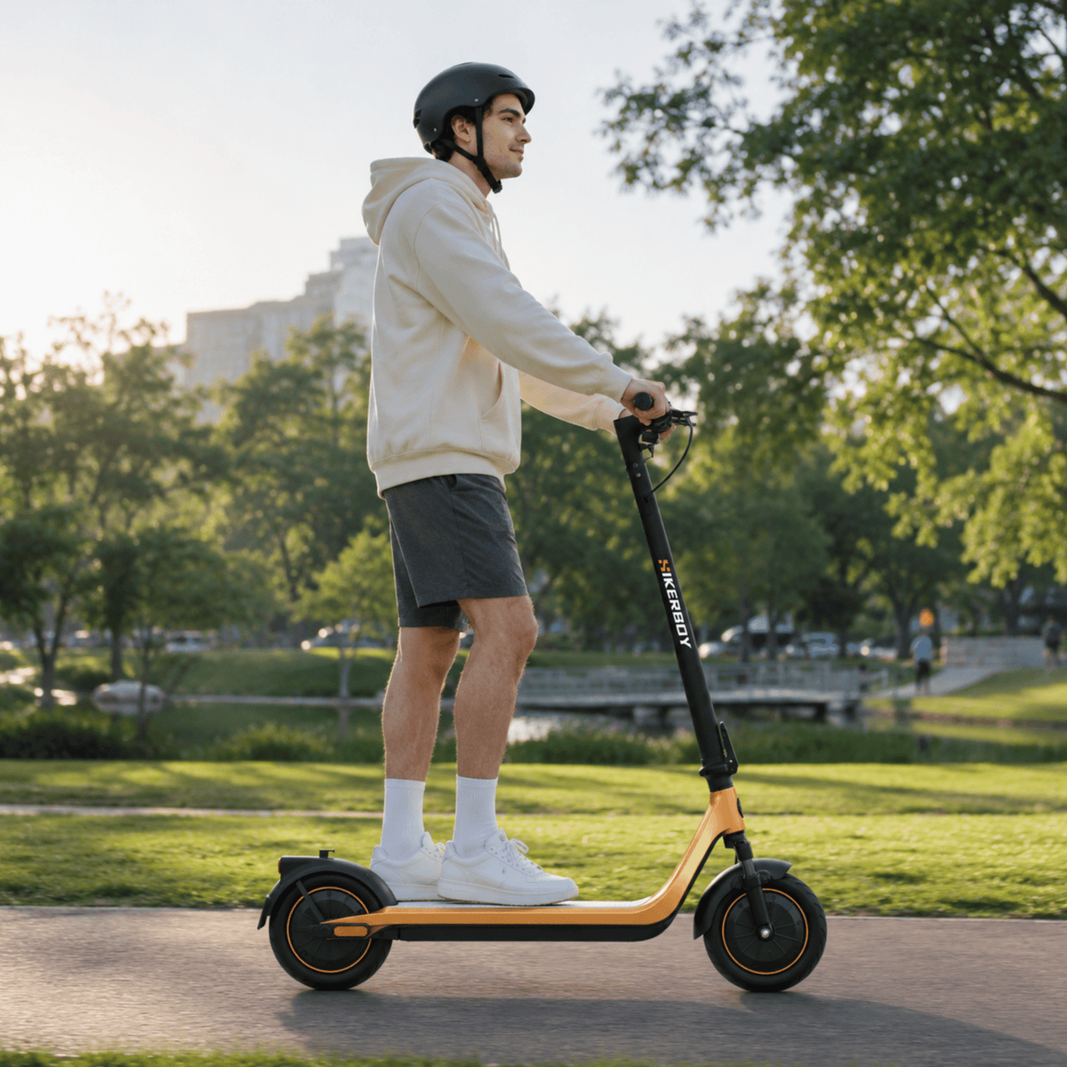Hombre de pie junto al patinete eléctrico HIKERBOY CURTIS DUAL PRO sobre el césped