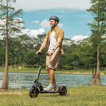 Hombre de pie junto al patinete eléctrico iENYRID A1 junto a un lago