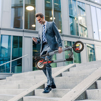 Persona llevando el patinete eléctrico iENYRID A1 plegado por la ciudad