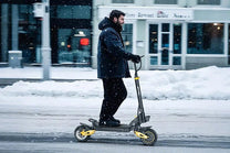 Hombre montando el patinete eléctrico iENYRID ES1 en la nieve