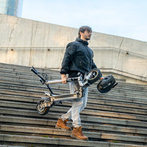 Persona llevando el patinete eléctrico iENYRID S1 plegado