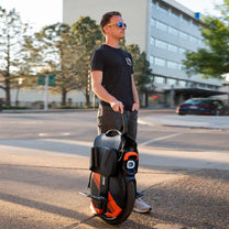 Hombre de pie junto al monociclo eléctrico InMotion V11Y en la ciudad