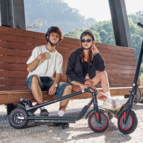 Persona sentada junto al patinete eléctrico iScooter i9M