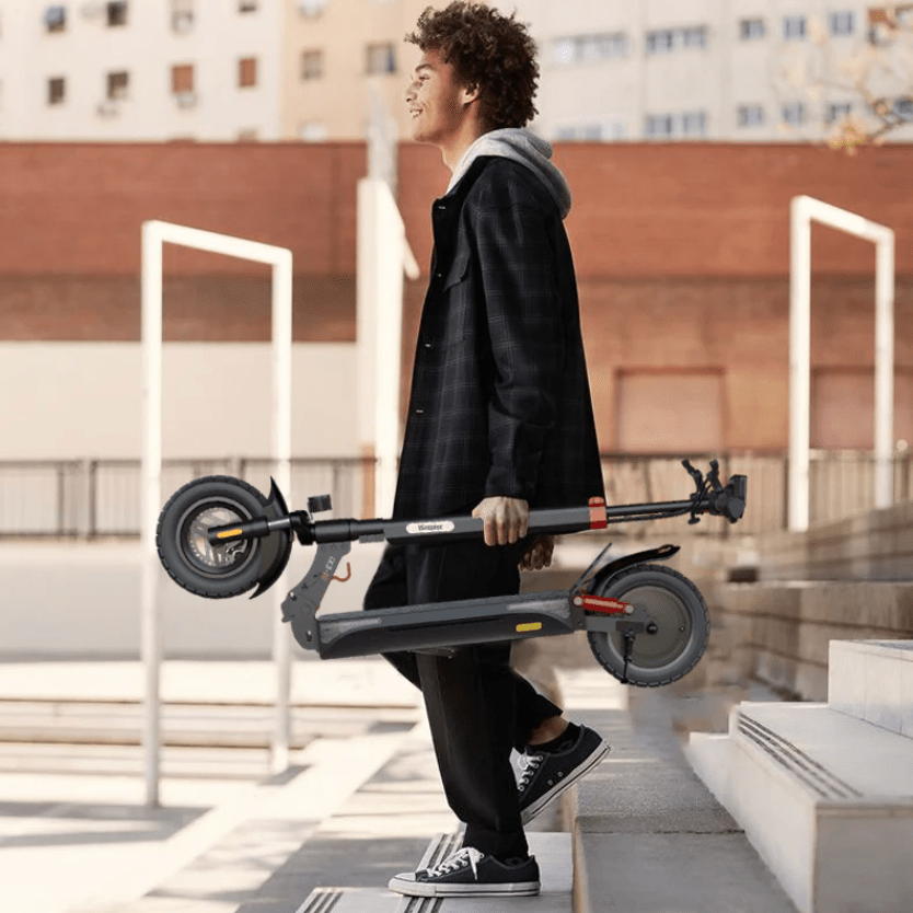 Persona llevando el patinete eléctrico iScooter iX3 plegado