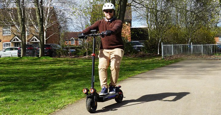 Persona de pie junto al patinete eléctrico iScooter iX4 sobre el césped