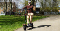 Persona de pie junto al patinete eléctrico iScooter iX4 sobre el césped