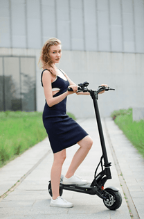 Mujer de pie junto al patinete eléctrico KAABO MANTIS 8 PLUS sobre el césped