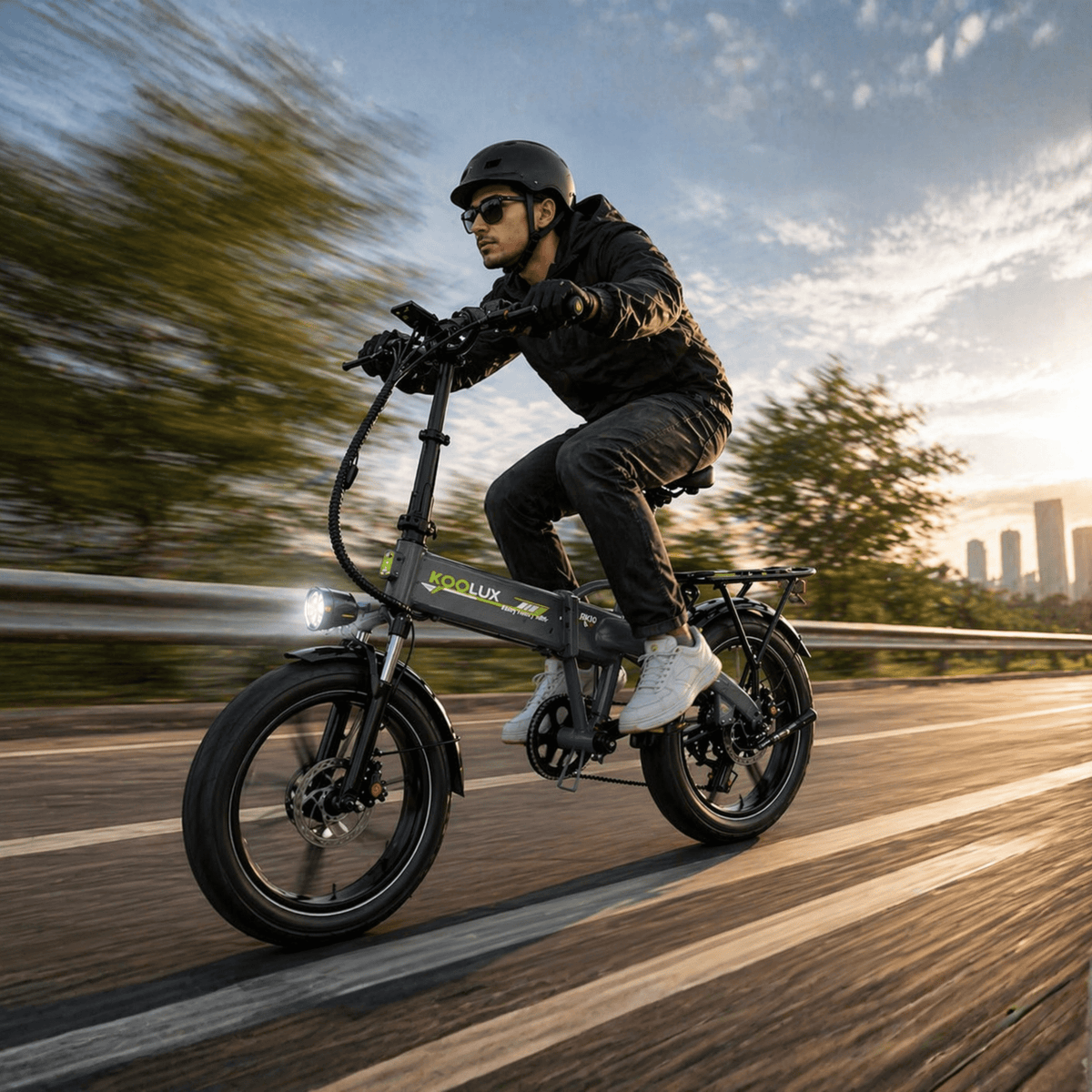 Hombre montando la bicicleta eléctrica plegable fat bike KOOLUX RK10 por la carretera al atardecer