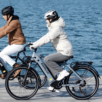 Dos personas con la bicicleta eléctrica KOOLUX X3 junto al mar