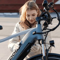 Mujer de pie junto a la bicicleta eléctrica KOOLUX X3 en la ciudad