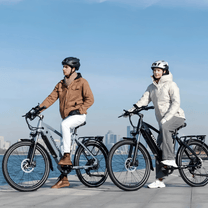 Dos personas con la bicicleta eléctrica KOOLUX X3 junto al mar