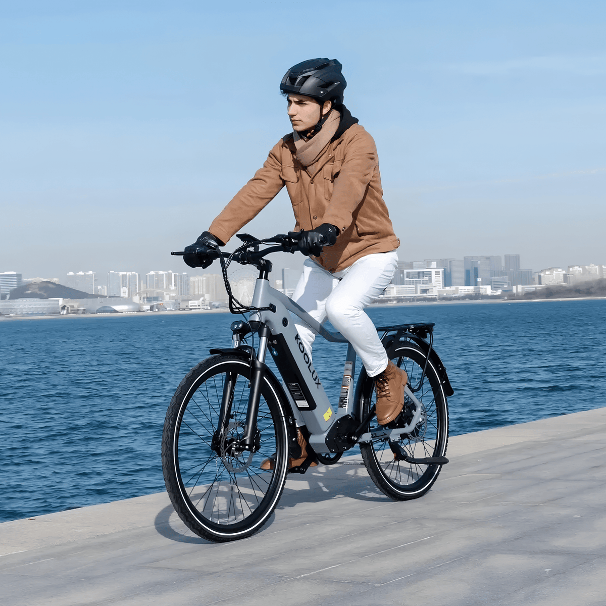 Hombre montando la bicicleta eléctrica KOOLUX X3 junto al mar