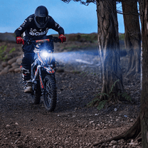 Moto cross eléctrica KuKirin X1 con las luces encendidas en un ambiente nocturno