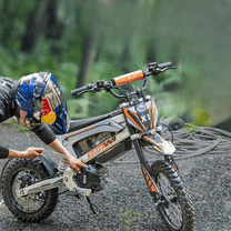 Persona de pie junto a la moto cross eléctrica KuKirin X1 en el bosque