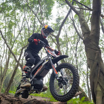 Piloto con la moto cross eléctrica KuKirin X1 fuera de pista en el bosque