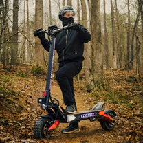 Hombre de pie junto al patinete eléctrico Nanrobot LS7+ en el bosque