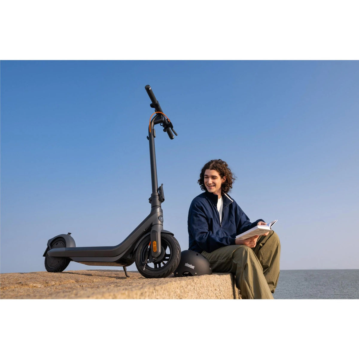 Persona sentada junto al patinete eléctrico Segway Ninebot E2 Pro