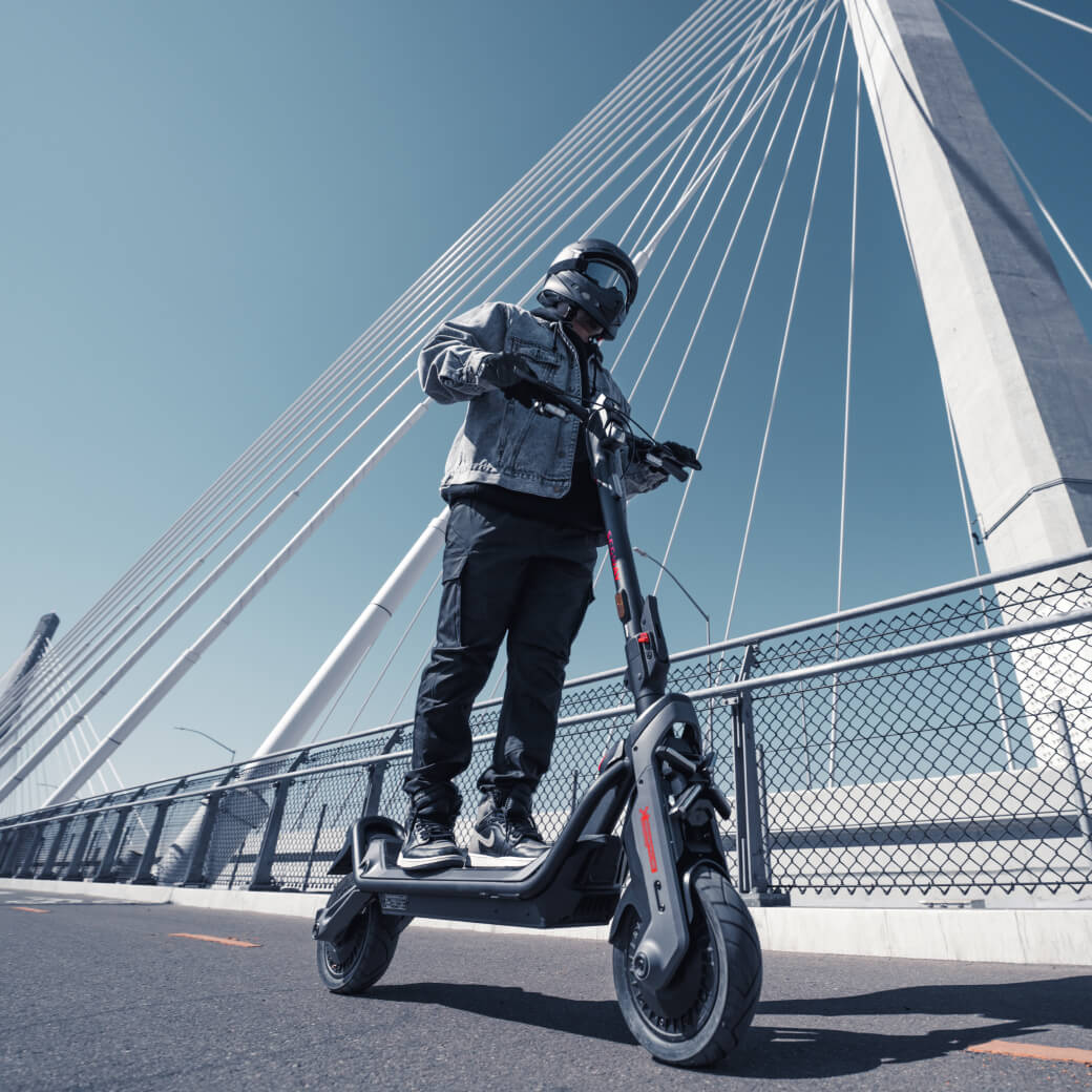Persona circulando con el patinete eléctrico Segway Ninebot GT3 por la ciudad sobre un puente
