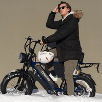 Hombre de pie junto a la bicicleta eléctrica fat bike Onemile P40 Pro en un paisaje invernal bajo el sol