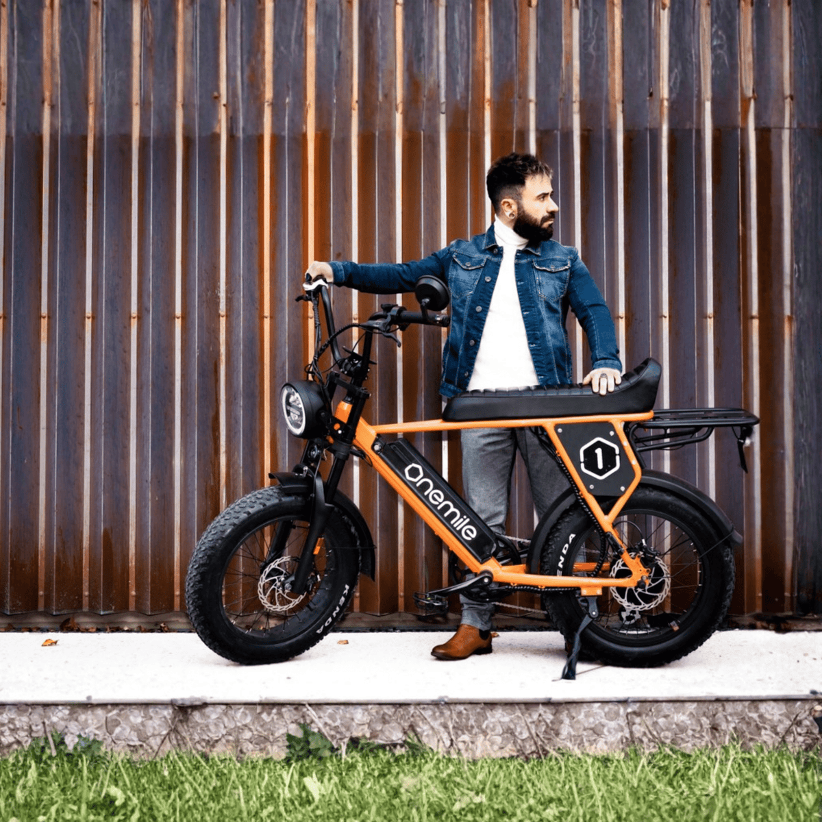 Hombre de pie junto a la bicicleta eléctrica fat bike Onemile P40 Pro en color naranja bajo el sol