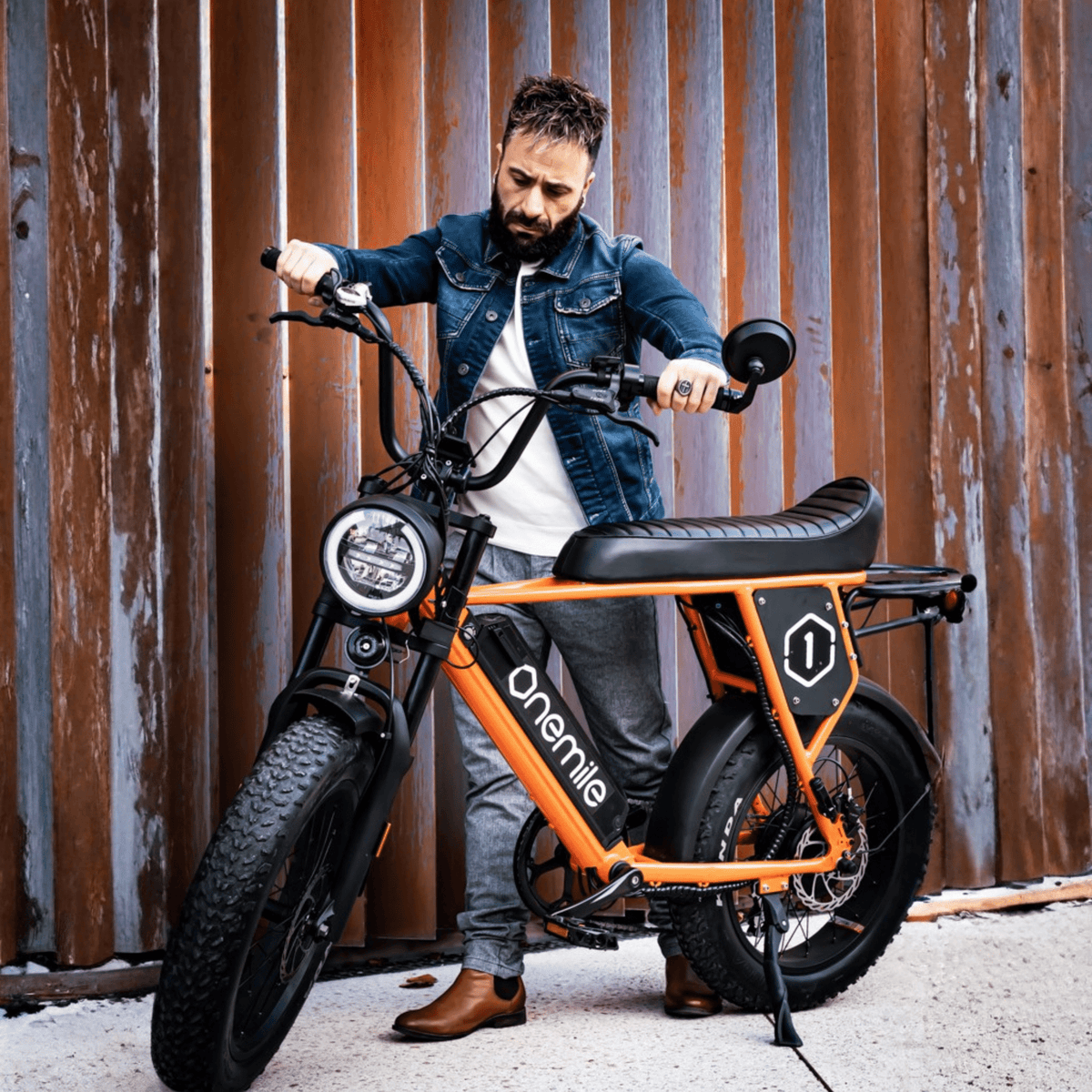 Hombre de pie junto a la bicicleta eléctrica fat bike Onemile P40 Pro en color naranja
