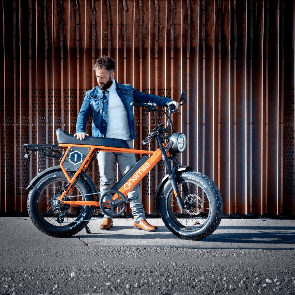 Hombre de pie junto a la bicicleta eléctrica fat bike Onemile P40 Pro en color naranja