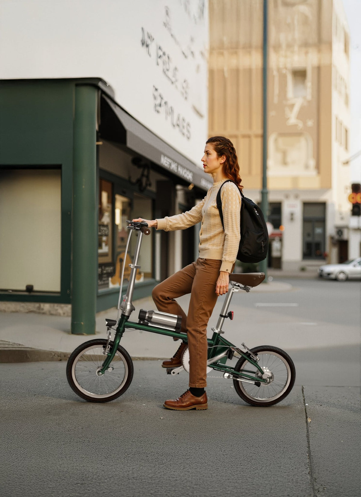 Mujer de pie junto a la bicicleta eléctrica plegable OneSport OT02 durante el plegado por una calle