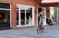 Mujer montando la bicicleta eléctrica plegable OneSport OT02 por una calle