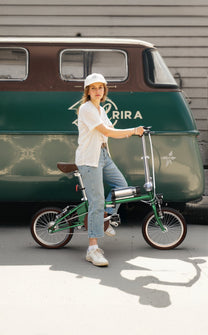 Mujer de pie junto a la bicicleta eléctrica plegable OneSport OT02 por una calle