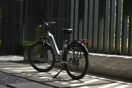 Bicicleta eléctrica OneSport OT05 vista de lado aparcada bajo el sol