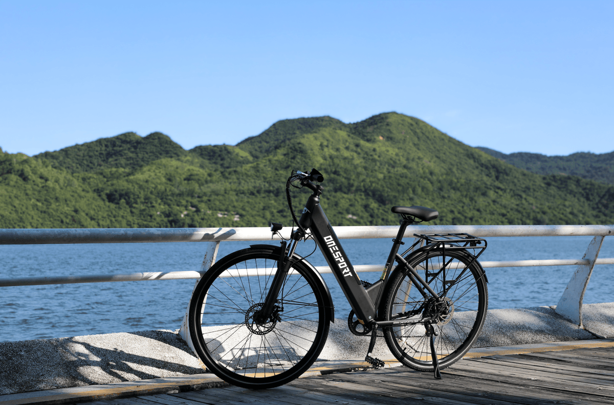 Bicicleta eléctrica OneSport OT12 en vista frontal en ángulo en color negro junto al mar