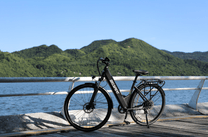 Bicicleta eléctrica OneSport OT12 en vista frontal en ángulo en color negro junto al mar