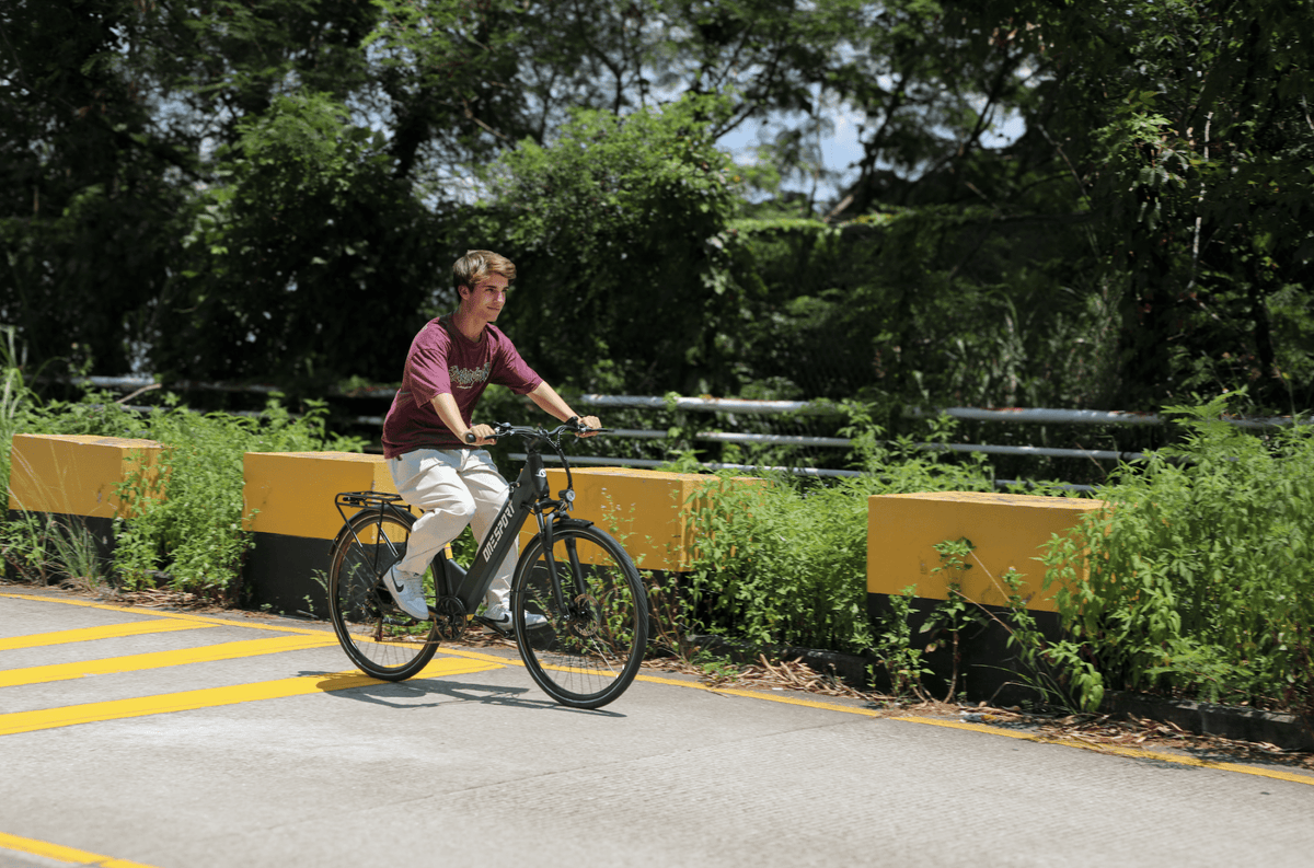 Persona montando la bicicleta eléctrica OneSport OT12 en color negro en un parque