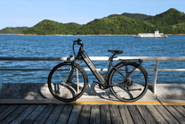 Bicicleta eléctrica OneSport OT12 vista de lado en color negro aparcada junto al mar