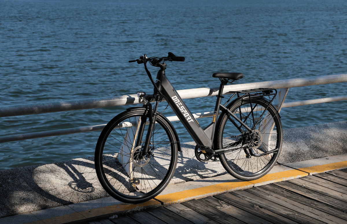 Bicicleta eléctrica OneSport OT12 en vista frontal en ángulo en color negro al atardecer